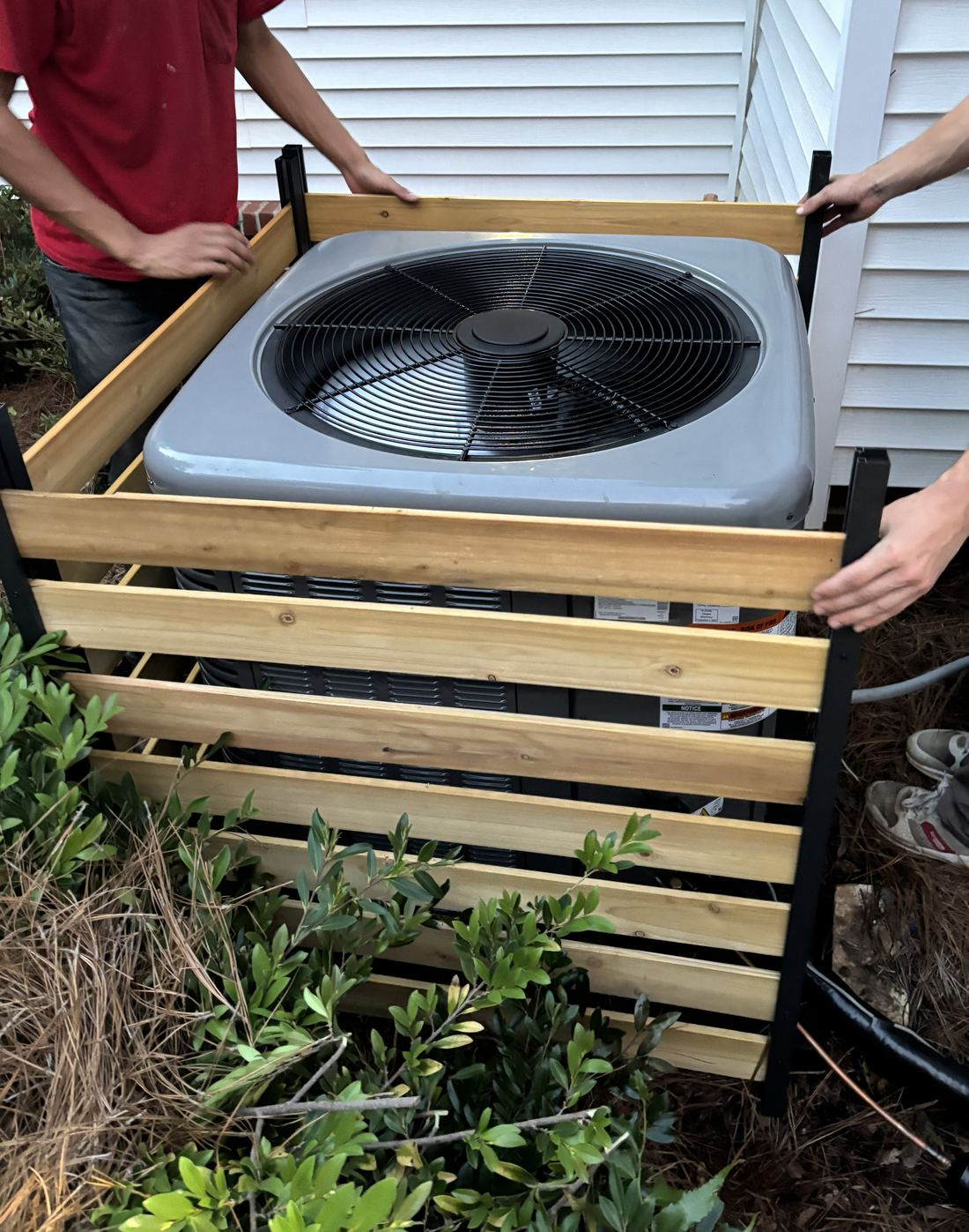 Engle Heating & Air technicians building a protective enclosure around a new outdoor AC unit