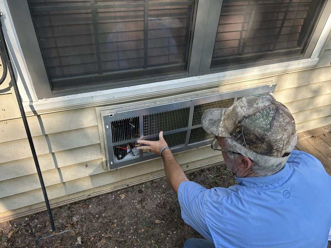 Allen Engle inspecting an indoor AC vent during a service call